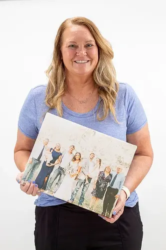 Stephanie H. smiles while holding a family photo at Peachtree City dental practice.