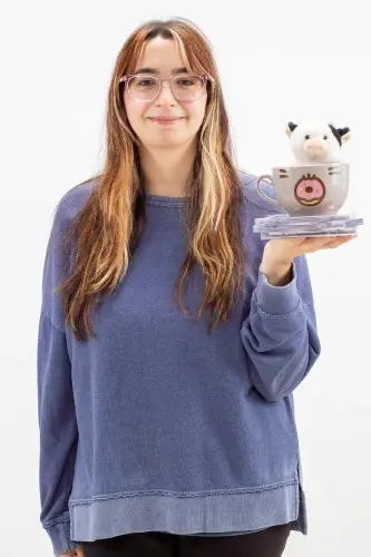 Young woman with glasses holding a cute cow-themed dental toy in Peachtree City.