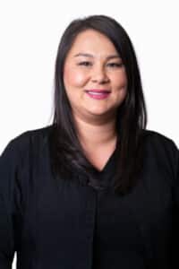 Professional headshot of a woman with long dark hair wearing a black top against a white background.