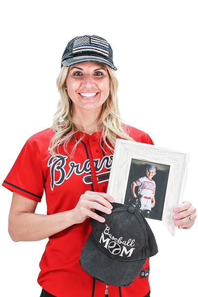 Woman in Braves baseball attire holding dental partner promotional materials against white background.