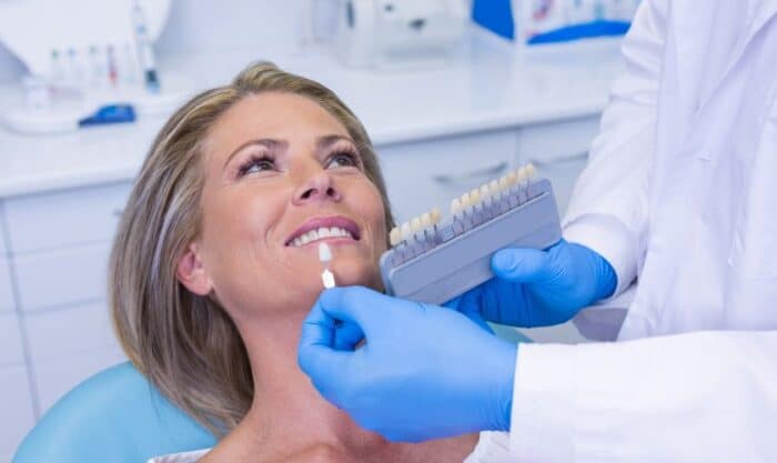 Woman receiving dental examination from dentist wearing blue gloves in modern dental office.