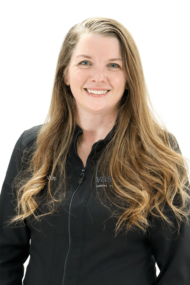 Professional headshot of woman with long brown hair smiling at camera wearing black jacket