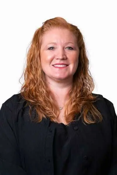Professional headshot of a woman with reddish-brown hair smiling at the camera in a black shirt.
