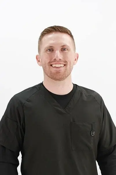 Dr. Pat smiles at Peachtree City dental practice wearing black scrubs.