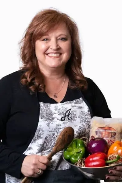 Smiling woman holding fresh vegetables and dental care products at Peachtree City dental practice.