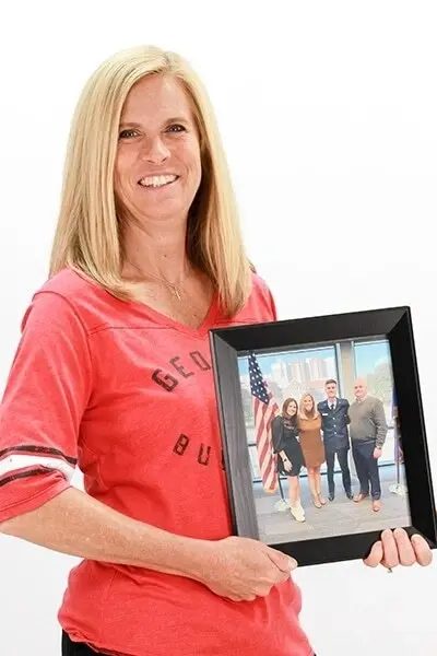 Woman in red shirt holding framed photo of dental team at Peachtree City practice.