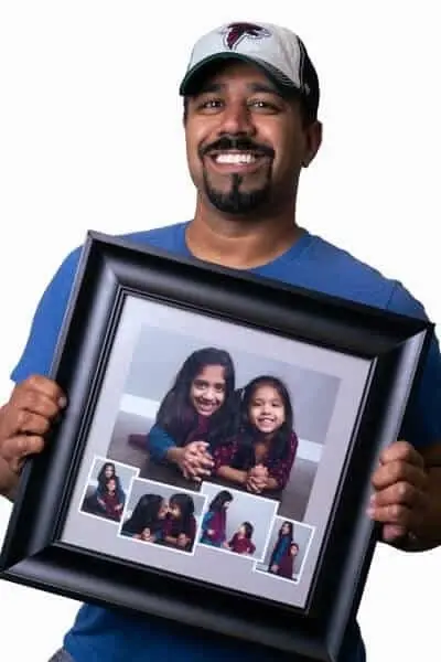 Dentist proudly holding framed family photos at Peachtree City dental practice.
