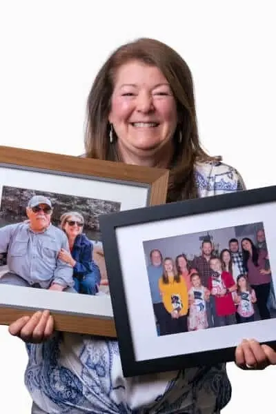 Woman holding framed family photos, smiling at dental practice in Peachtree City, Georgia.