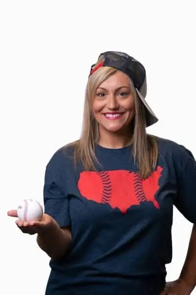 Smiling woman holding a baseball wearing a USA map baseball shirt and cap.