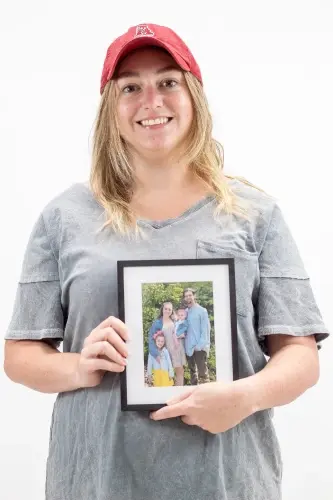 Smiling woman holding framed family photo in Peachtree City dental practice.