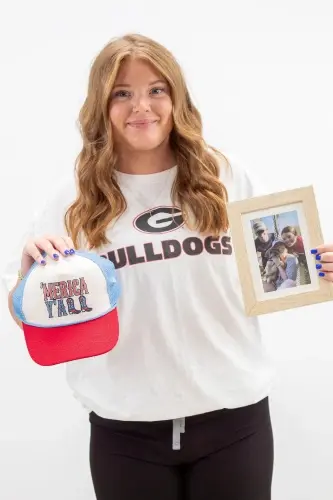 Kelsey S., team member at dental practice in Peachtree City, GA, holding Bulldogs merchandise and photo frame.