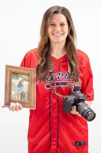 Samantha B., dental professional at Peachtree City practice, holding framed photo and camera.