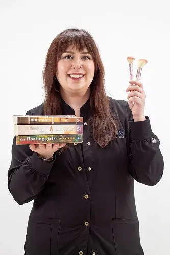 Sara S., dentist at Peachtree City dental practice, holding makeup brushes and books with a bright smile.